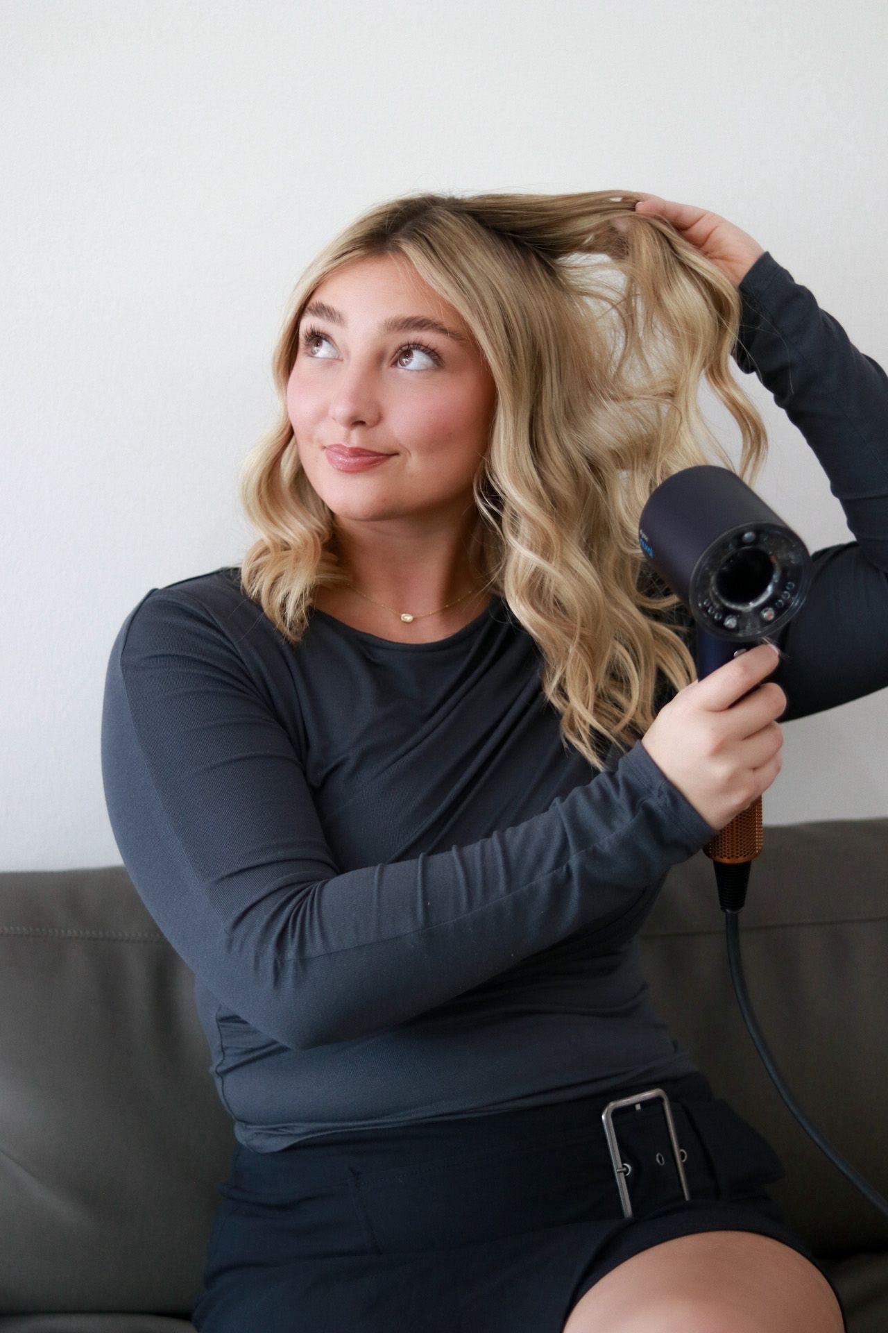 Hairstylist branding photos showing someone blow-drying their hair on a grey couch.