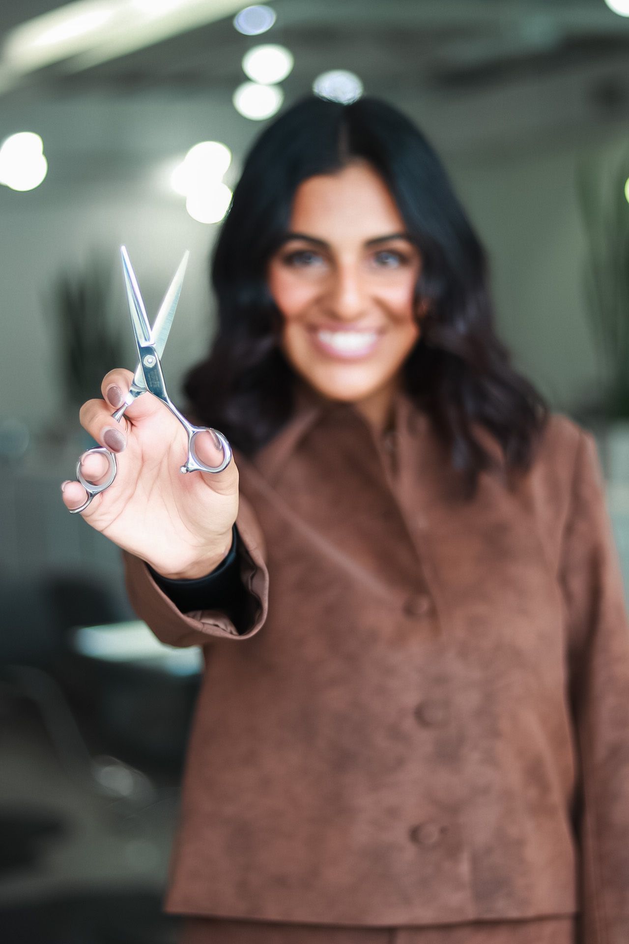 Close-up shots of someone wearing a brown suede showing their hairstylist shears.