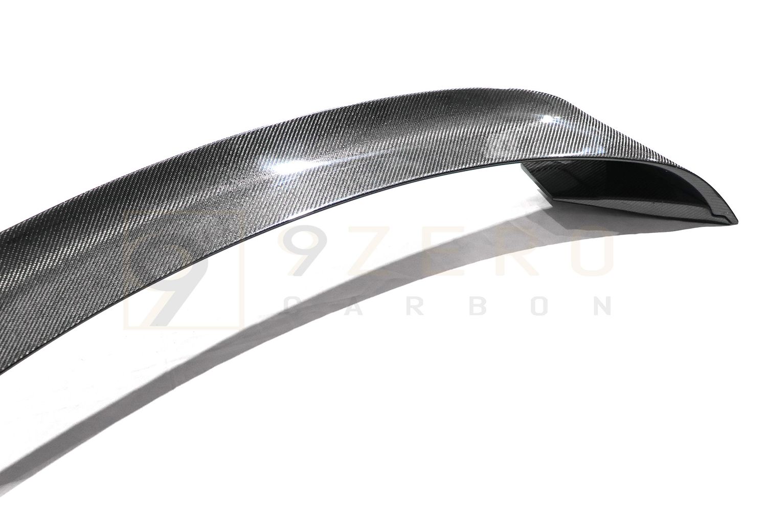 Close-up black and white photo of a curved metal blade or scythe showing its sleek contoured edge.