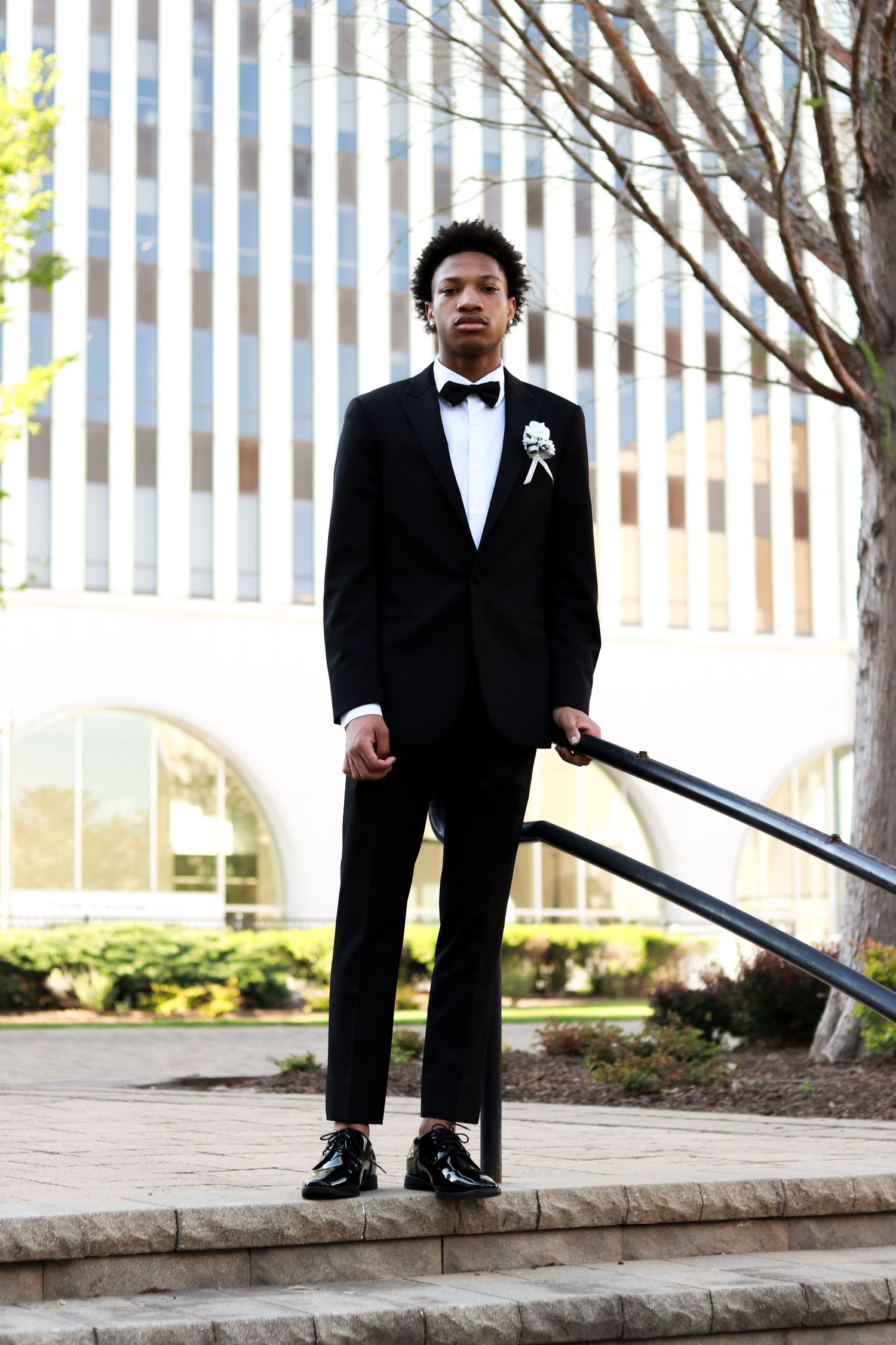 A series of photos showing a young ring bearer in a black tuxedo sitting on stone steps outdoors.