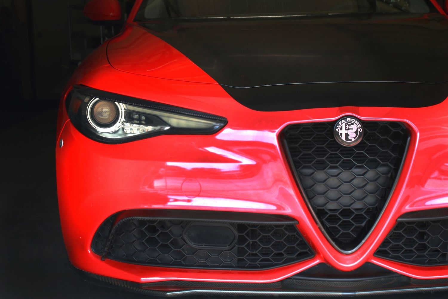 Front grille and headlight detail of a red Alfa Romeo sports car.
