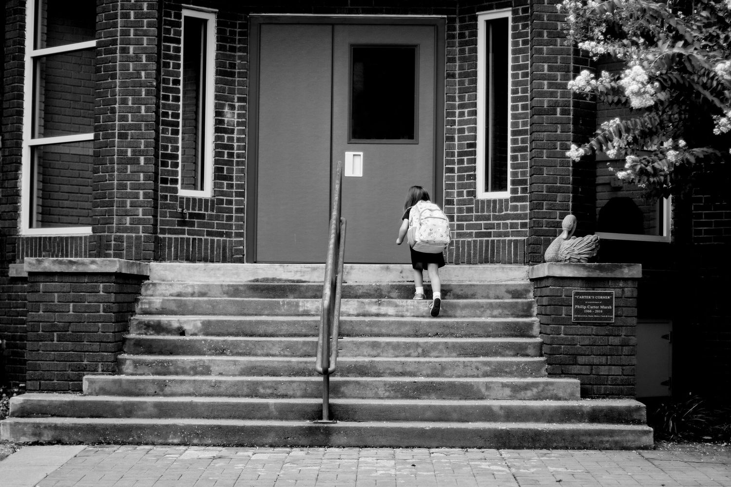 A sequence of four black and white photos showing someone jumping down brick steps in a skateboarding motion.