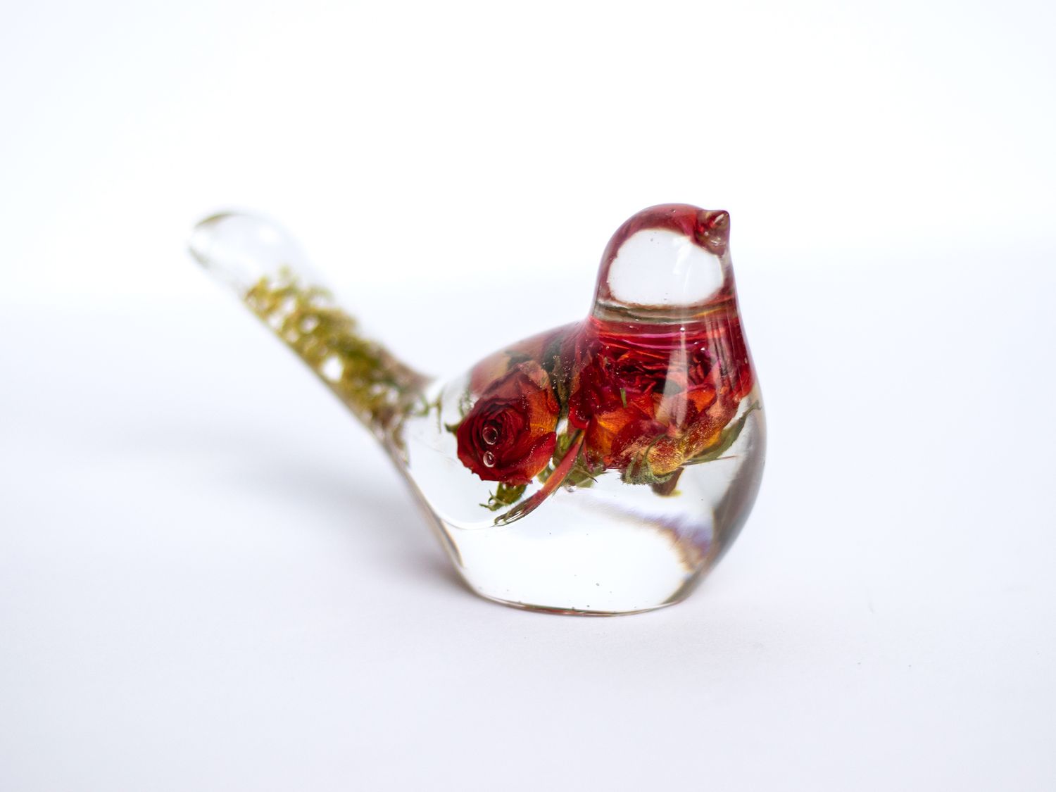 Clear glass bird figurine with red floral interior and gold-flecked tail, decorative art glass paperweight.