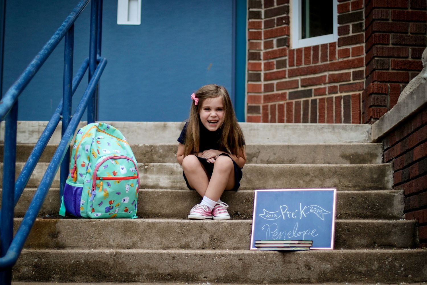Blue painted concrete steps with backpacks and school supplies arranged on them.