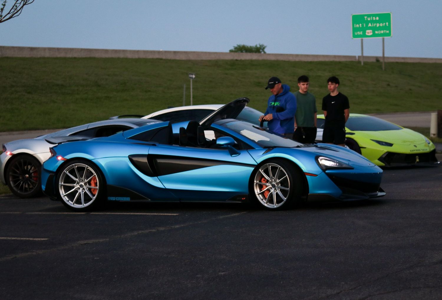 Row of colorful supercars including McLaren and Lamborghini models parked on display.