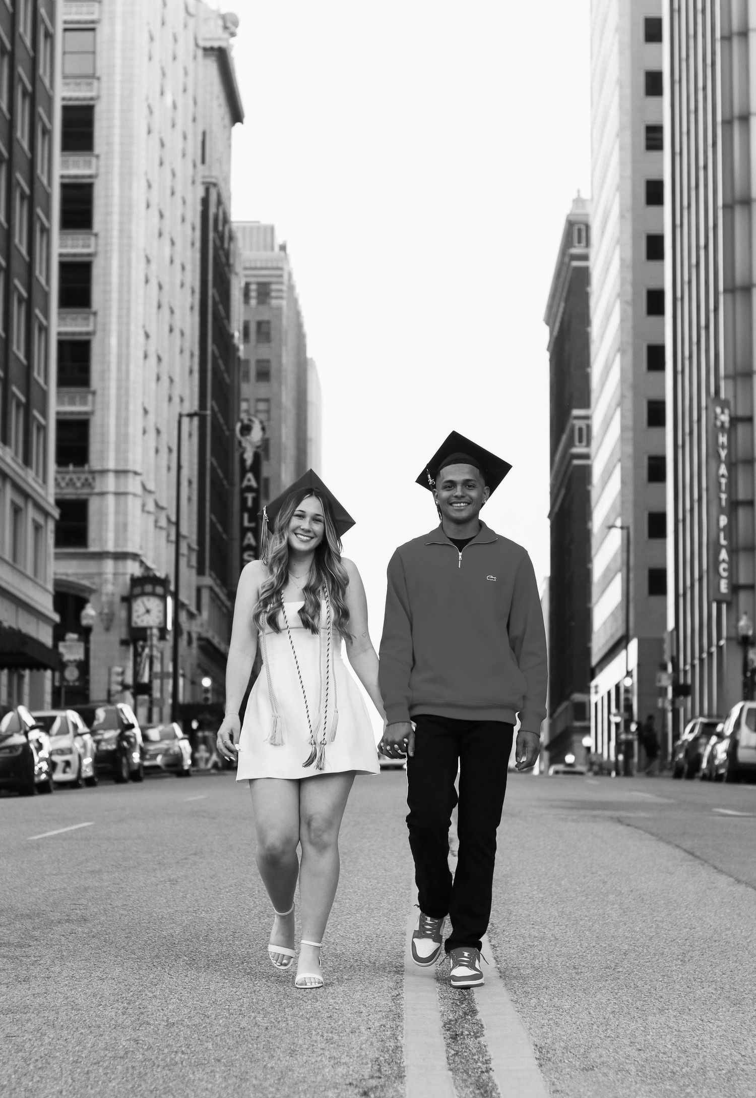 A series of black and white photos showing a couple walking together on a city street wearing graduation caps.