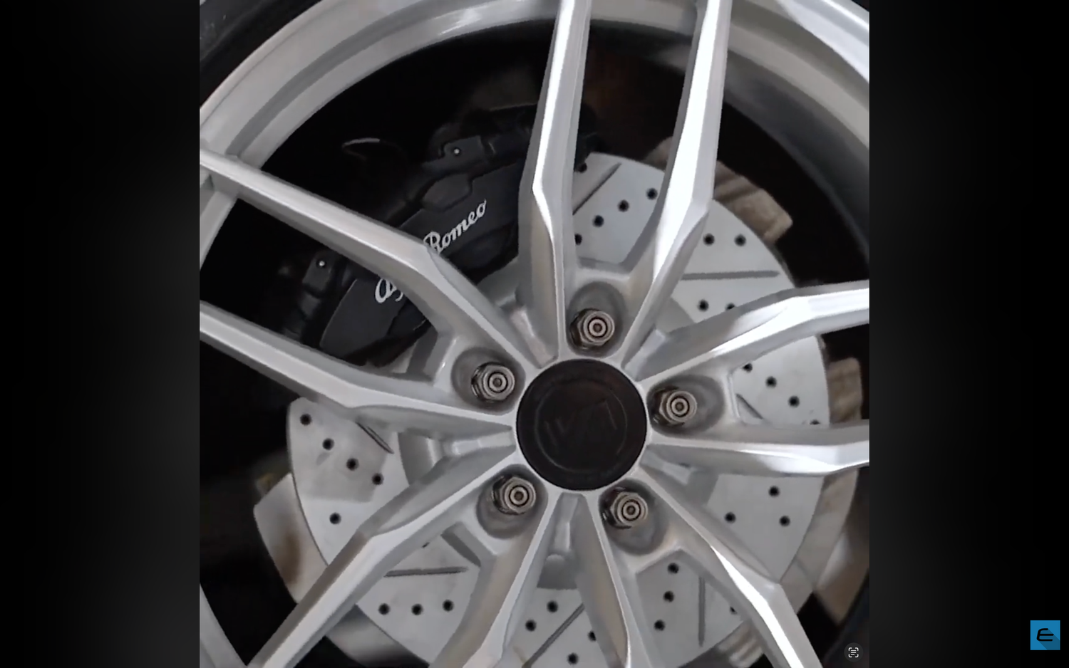 Close-up detail of silver alloy car wheel with drilled brake disc pattern.