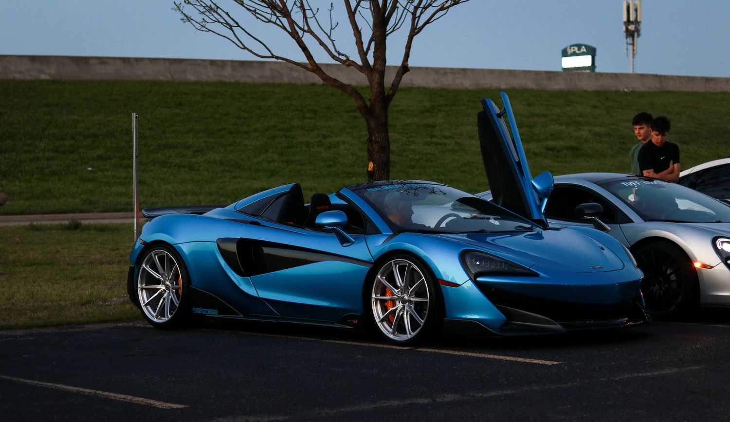 Line of blue McLaren supercars photographed from the side during a car meet.