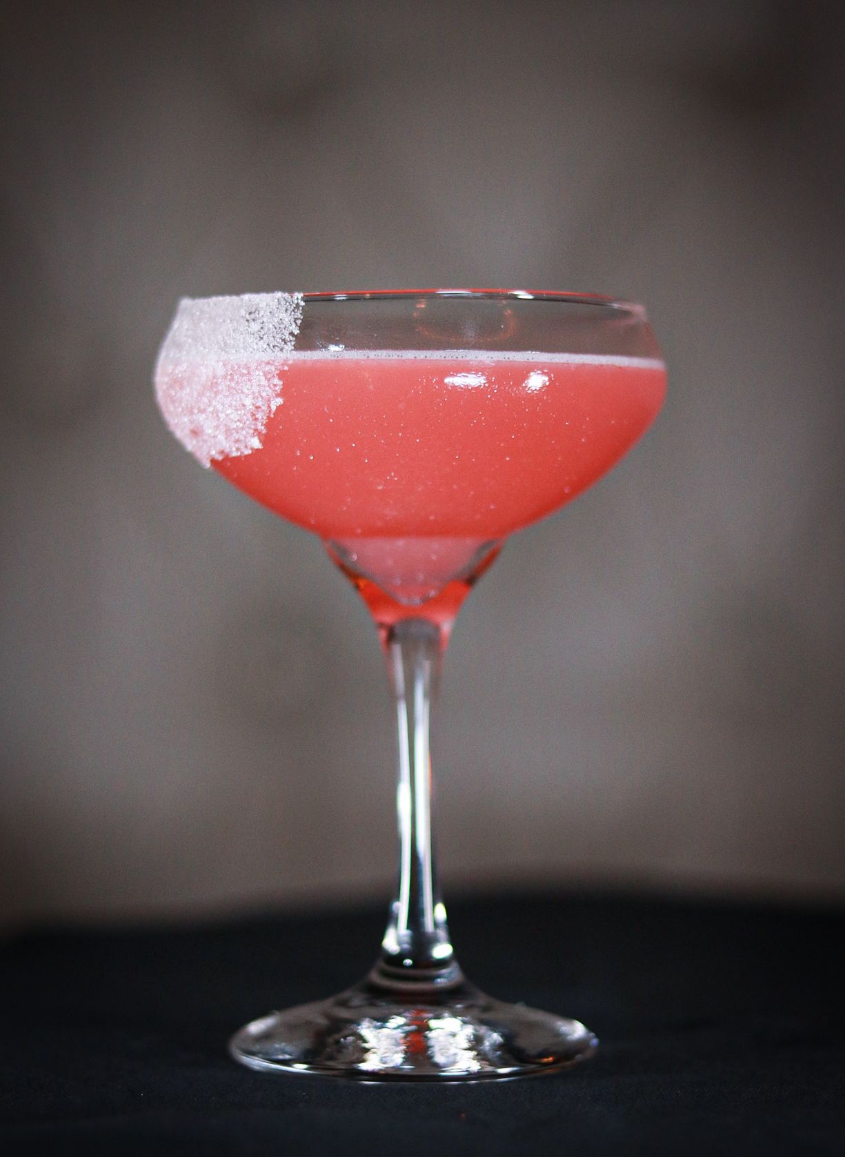 Pink cocktails in coupe glasses with sugar rim shown in sequential shots.