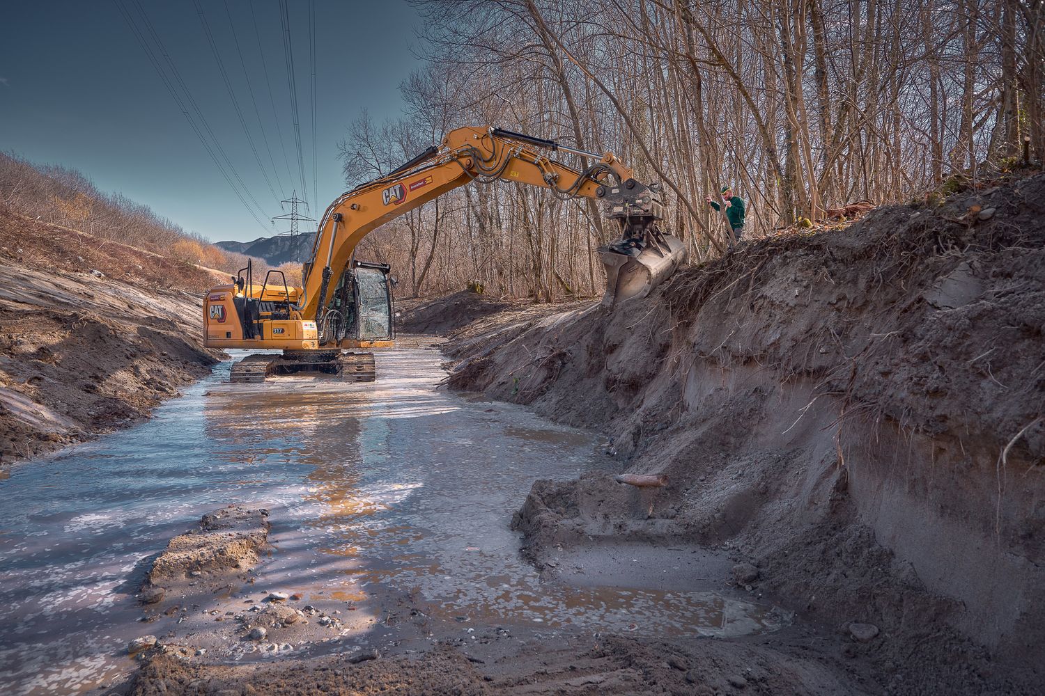 Fotografia di bulldozer cingolato CAT impegnato in lavori di bonifica in ambiente acquatico