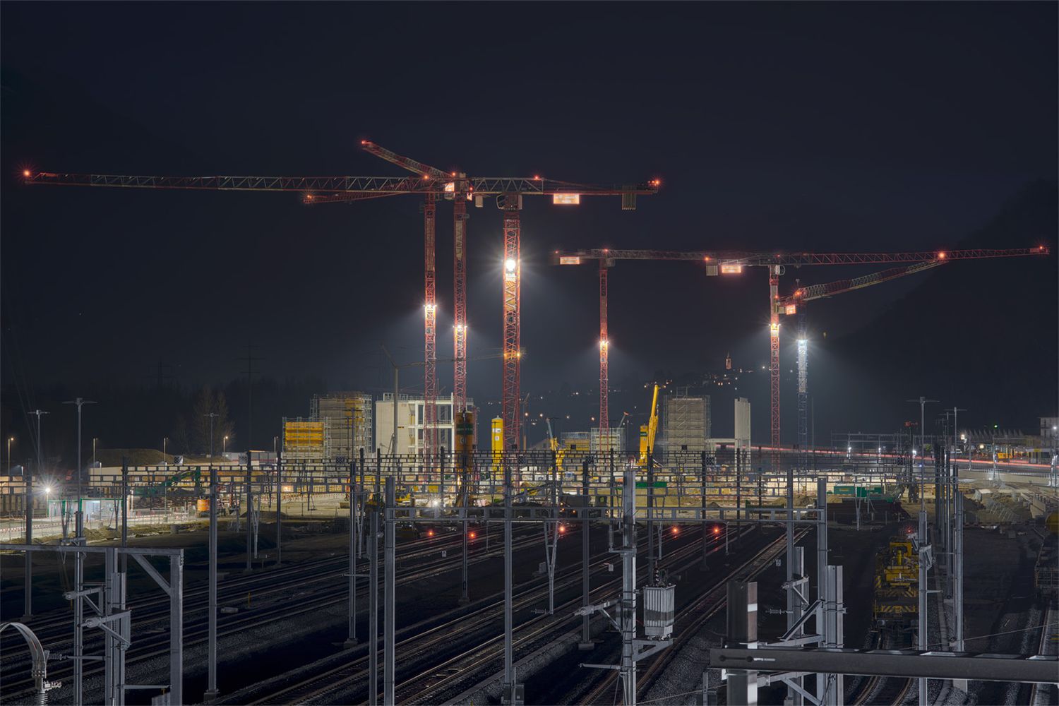 Cantiere ferroviario notturno con macchinari e illuminazione di lavoro durante interventi di manutenzione sulla linea ferroviaria.