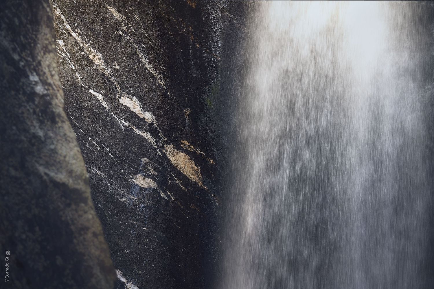 Porzione di cascata su roccia, movimento dell’acqua e materia naturale.