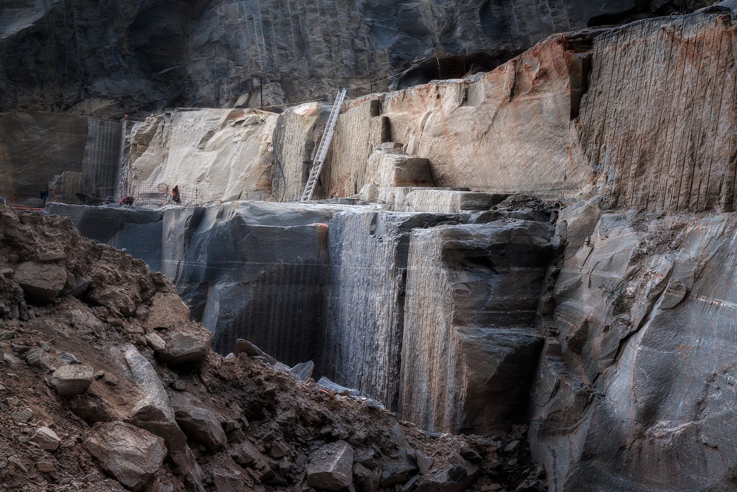 Parete di estrazione della cava in Val Calanca con scala e operai al lavoro – documentazione fotografica del territorio alpino.