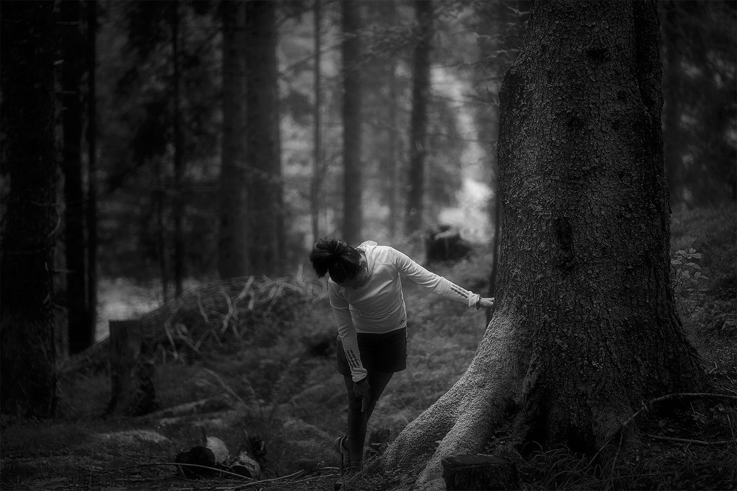 Ritratto in bianco e nero di una ragazza appoggiata a un albero, gesto intimo luce morbida che rivelano presenza, emozione,ascolto interiore