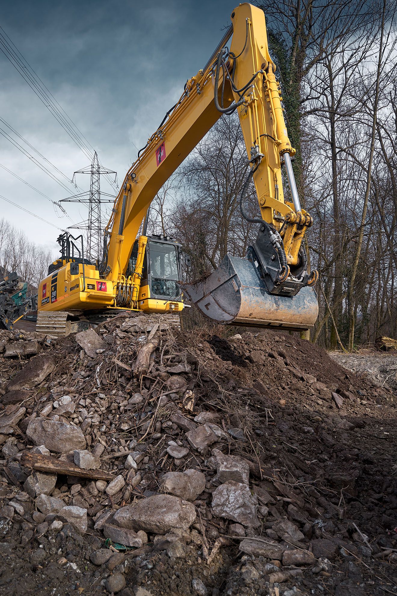Escavatore cingolato al lavoro su cumulo di terra in cantiere in Ticino, documentazione fotografica operativa.