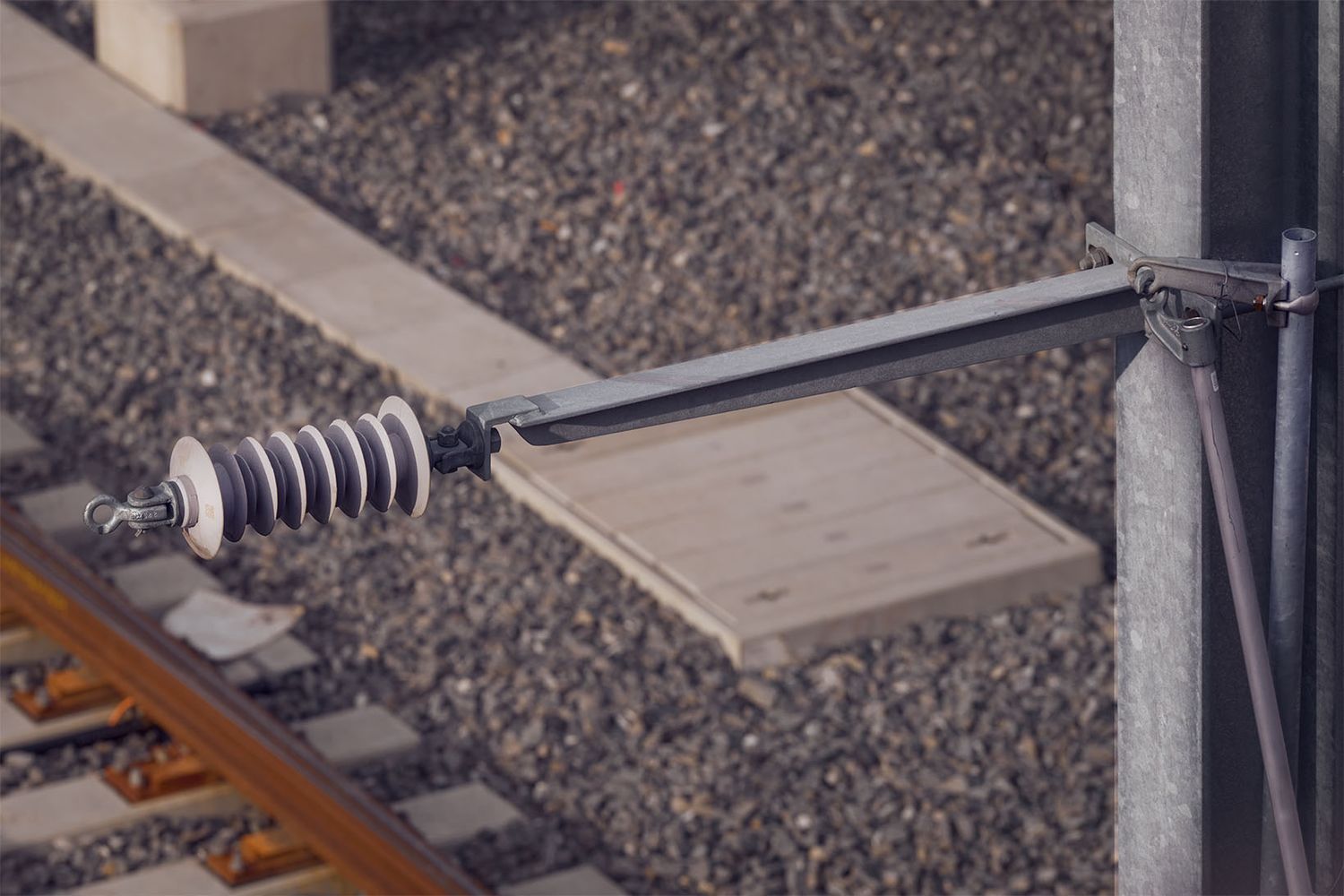 Dettaglio tecnico della linea aerea ferroviaria con isolatore e supporto metallico sopra i binari nel cantiere ferroviario.