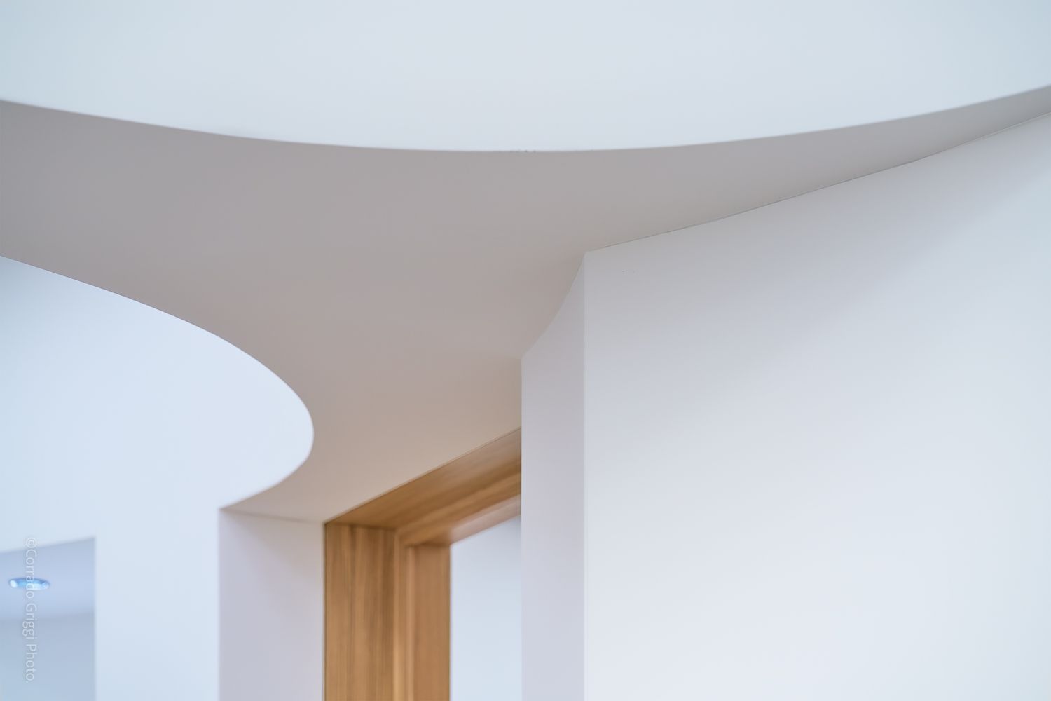 Struttura architettonica interna di colore bianco, linee curve e superfici luminose che definiscono lo spazio.