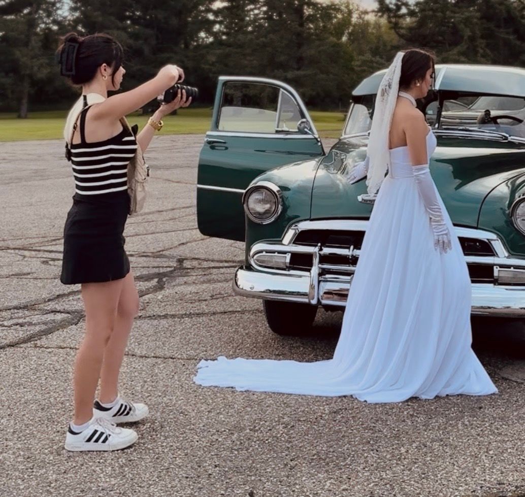 A BTS photo of the owner of Coley Rose Co. taking photos of a bride next to a vintage car.