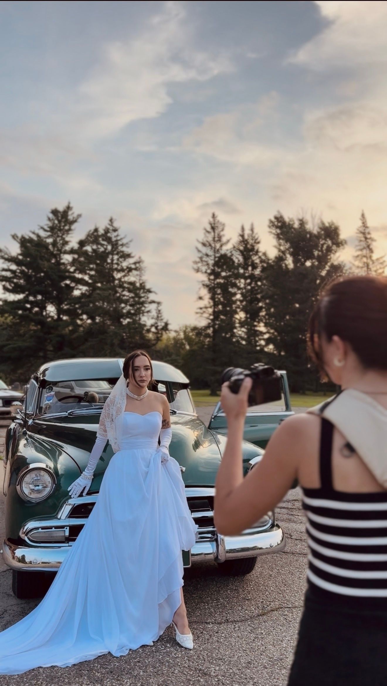 A BTS photo of the owner of Coley Rose Co. taking photos of a bride next to a vintage car.