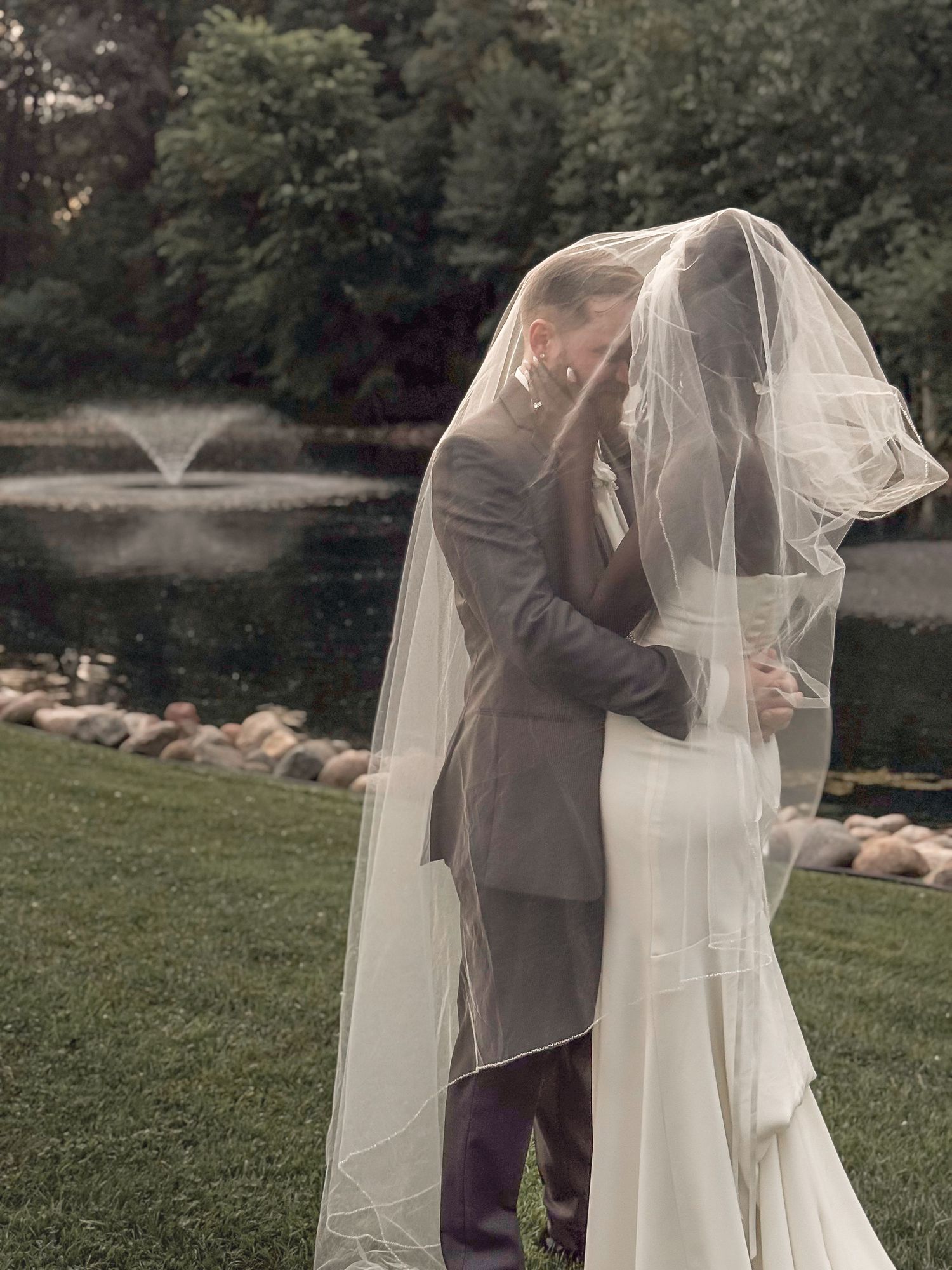 Bride and groom sharing a moment post-ceremony by the waterfront and water fountain.
