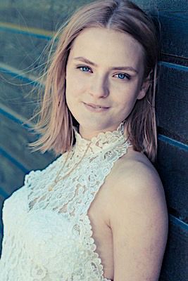 Portrait shot featuring delicate white lace high neck top against a dark background with natural lighting effects.