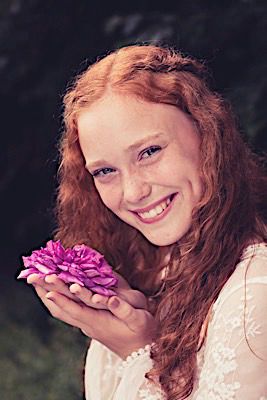 Portrait with vibrant pink flower showing natural curls and delicate lace detail.