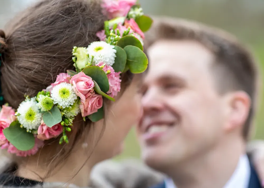 Close-up of bride wearing floral crown with pink roses and white flowers.
