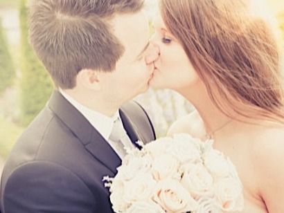 Romantic wedding kiss portrait with soft focus and white rose bouquet.