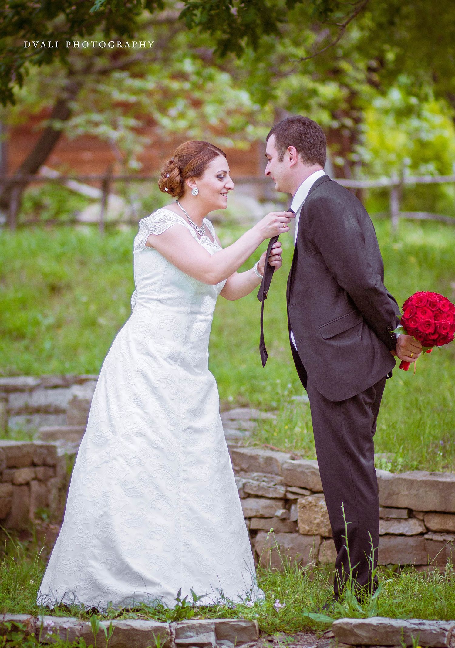 A playful wedding moment captured outdoors on stone steps surrounded by greenery.