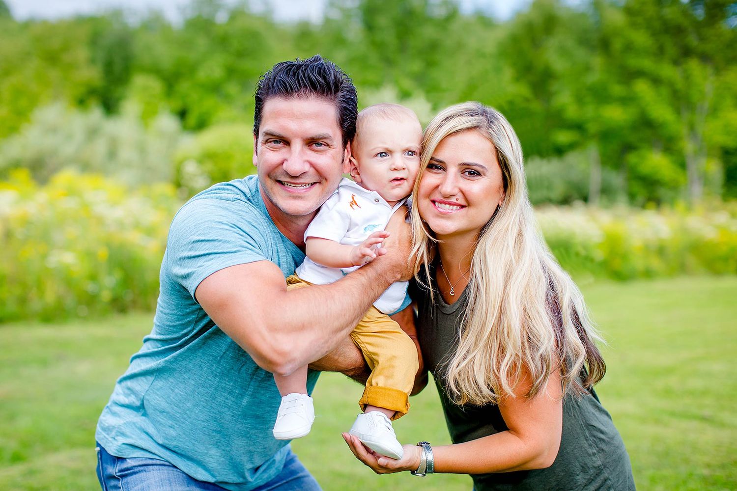 Family enjoying a playful moment together on a sunny day in a grassy field.