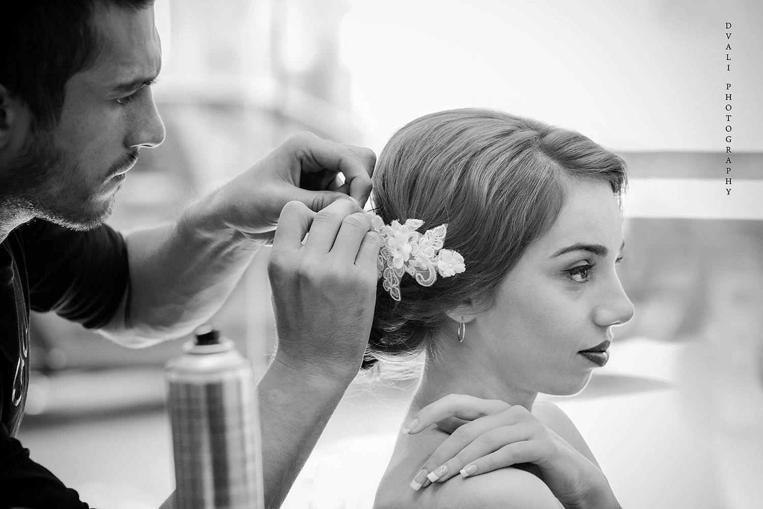 A stylist adds finishing touches to a bride's elegant hair arrangement.