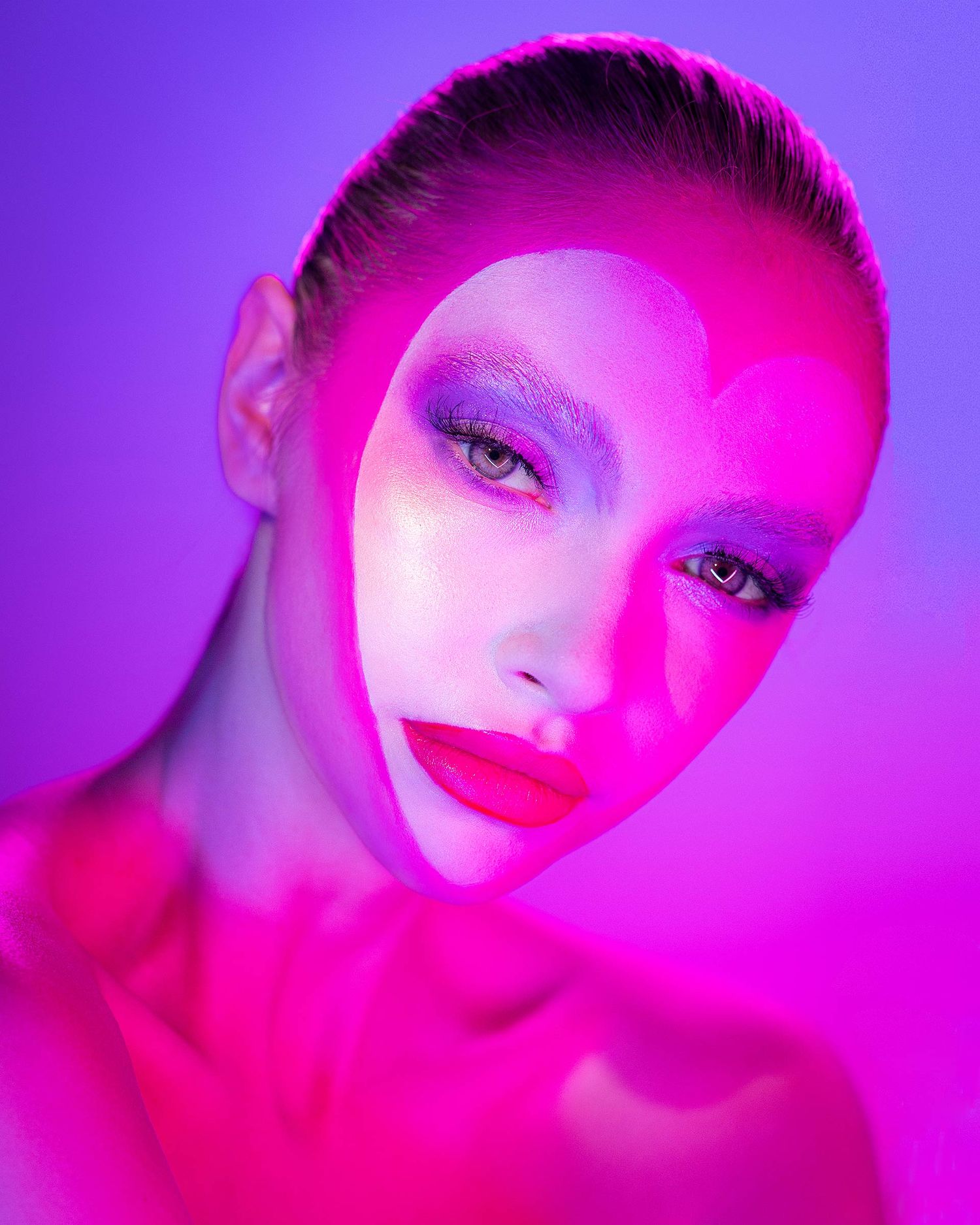 Artistic beauty portrait with dramatic pink and purple lighting creating a striking contrast effect.