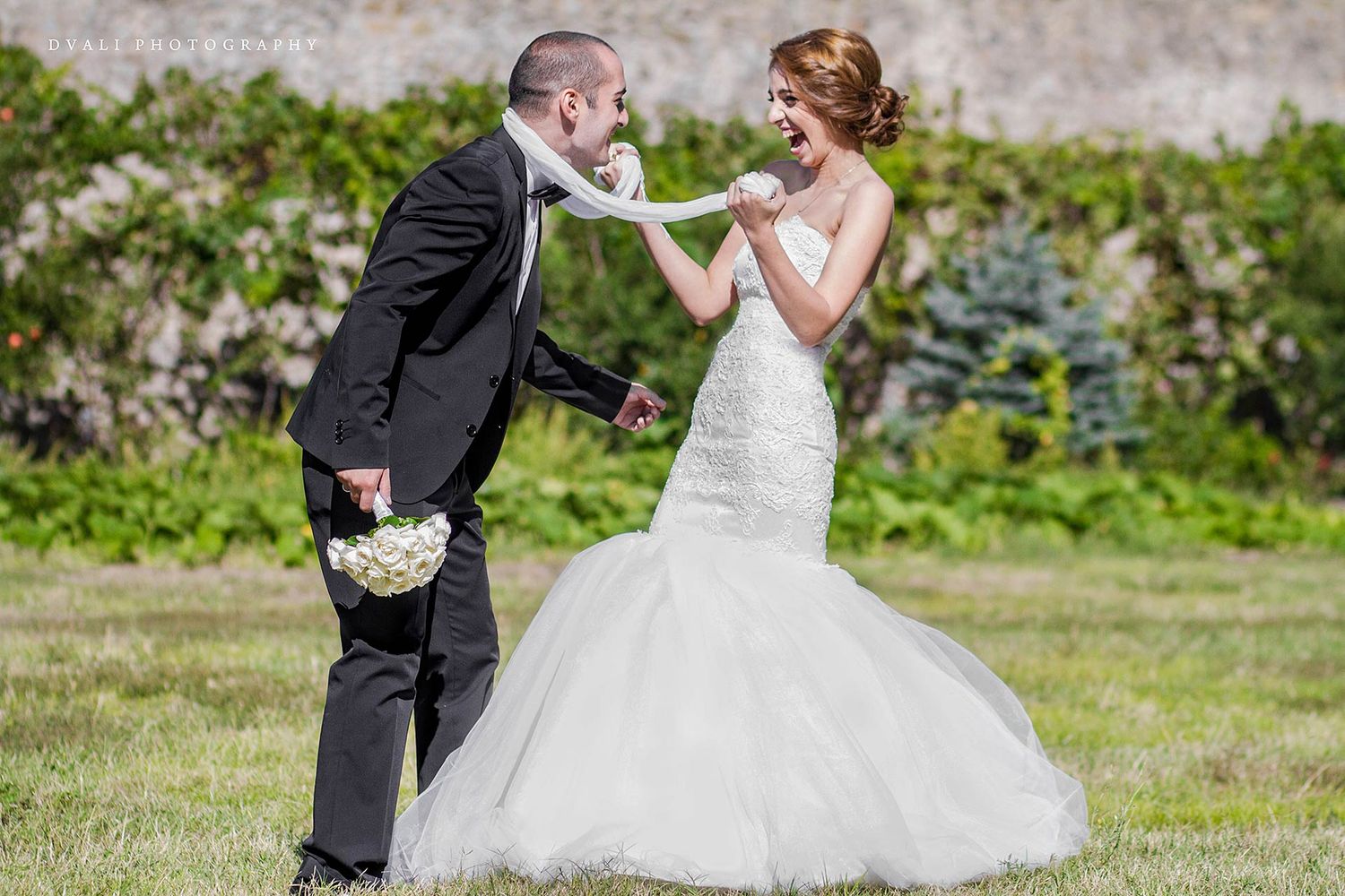 A joyful wedding moment captured outdoors with the bride's dress flowing in the breeze.