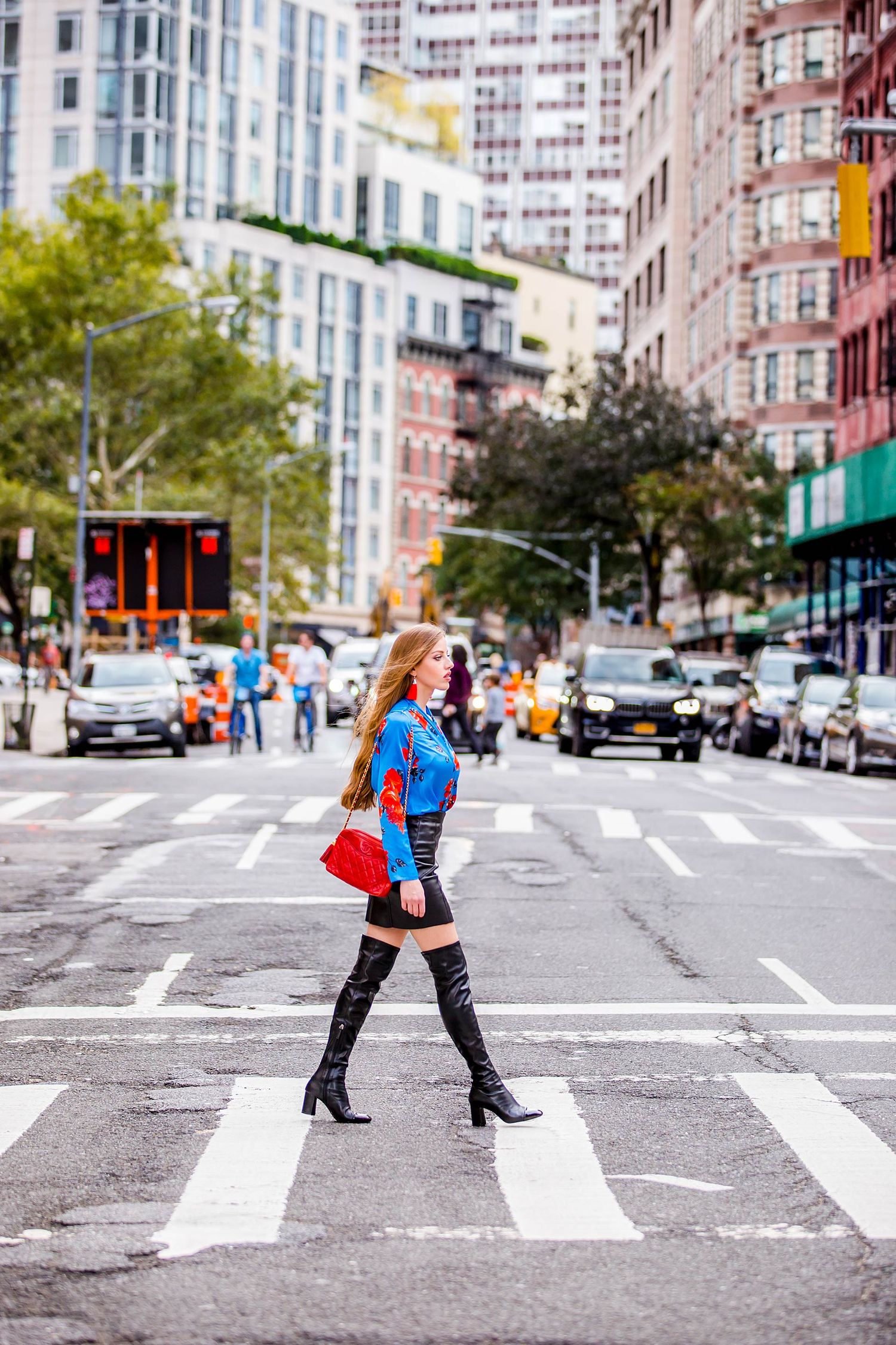 Casual chic outfit with denim jacket and knee-high boots on city crosswalk.