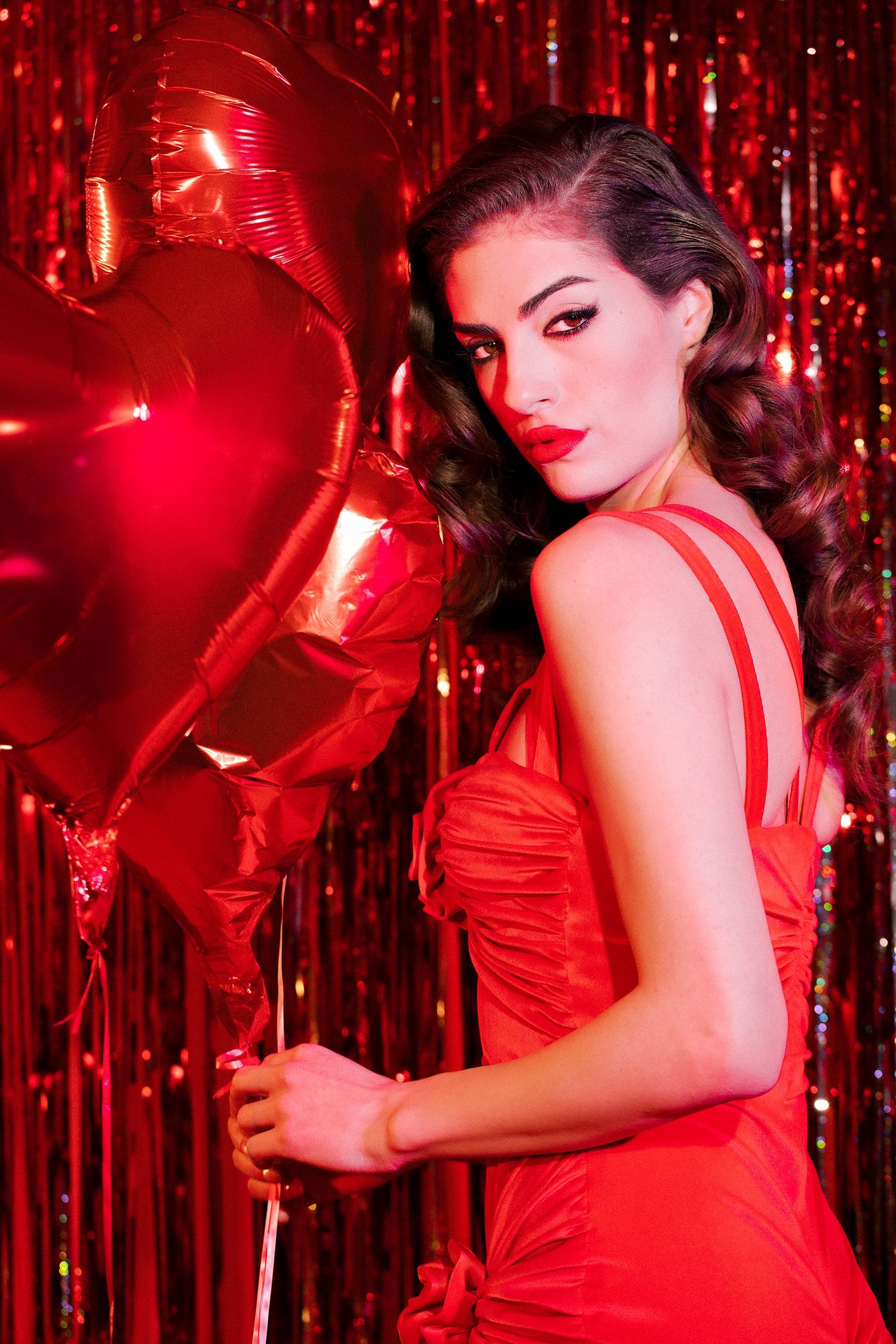 Elegant poses with star balloons against red sparkly backdrop in vintage style.