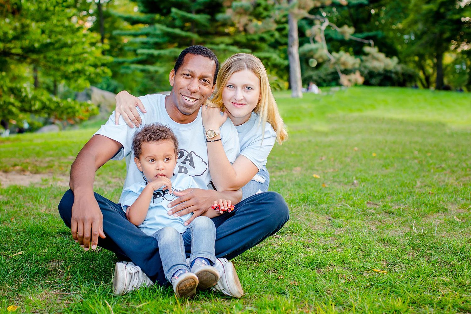 Family playing and laughing together on green grass in a park.