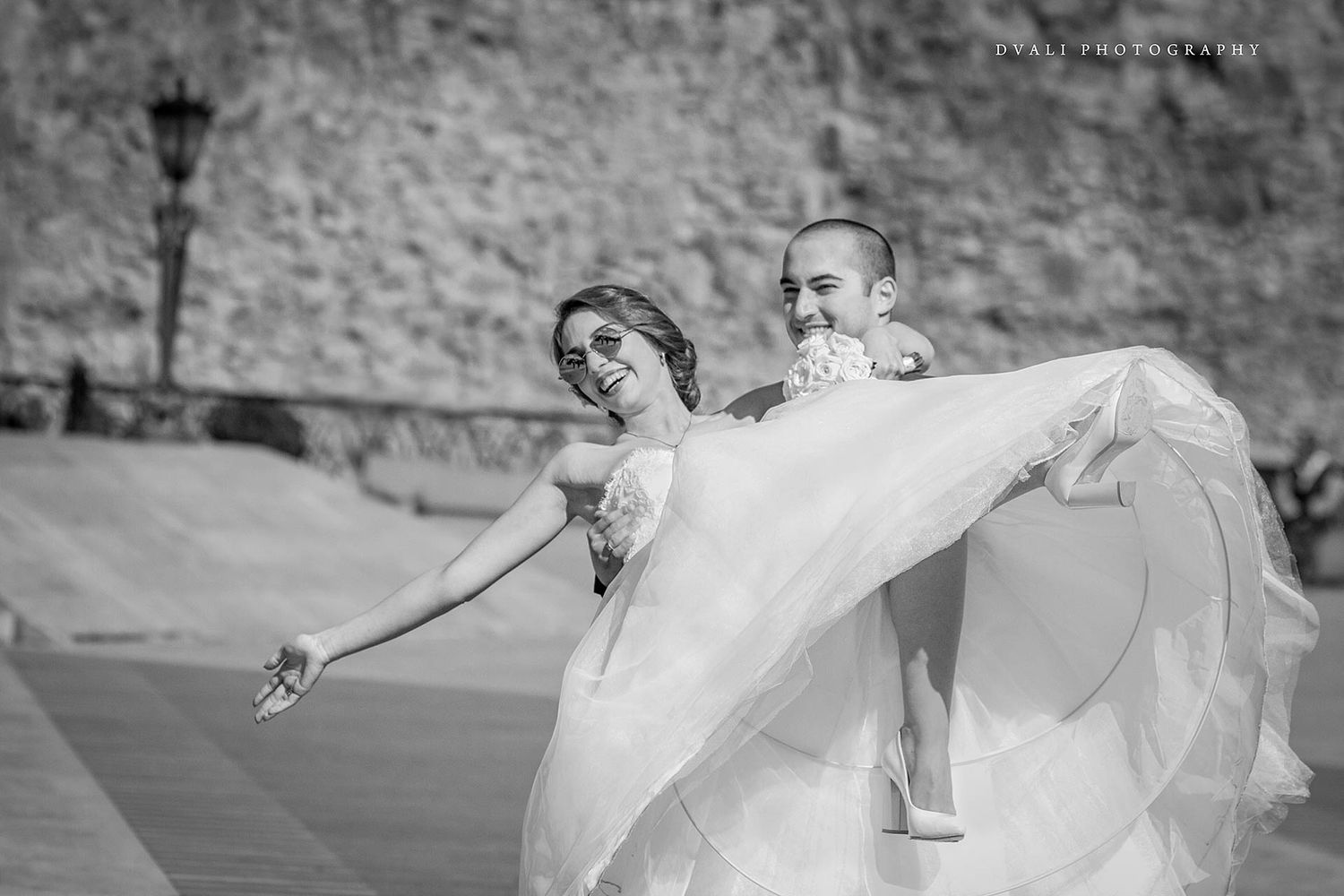 A romantic black and white moment of a couple dancing with flowing wedding dress fabric.