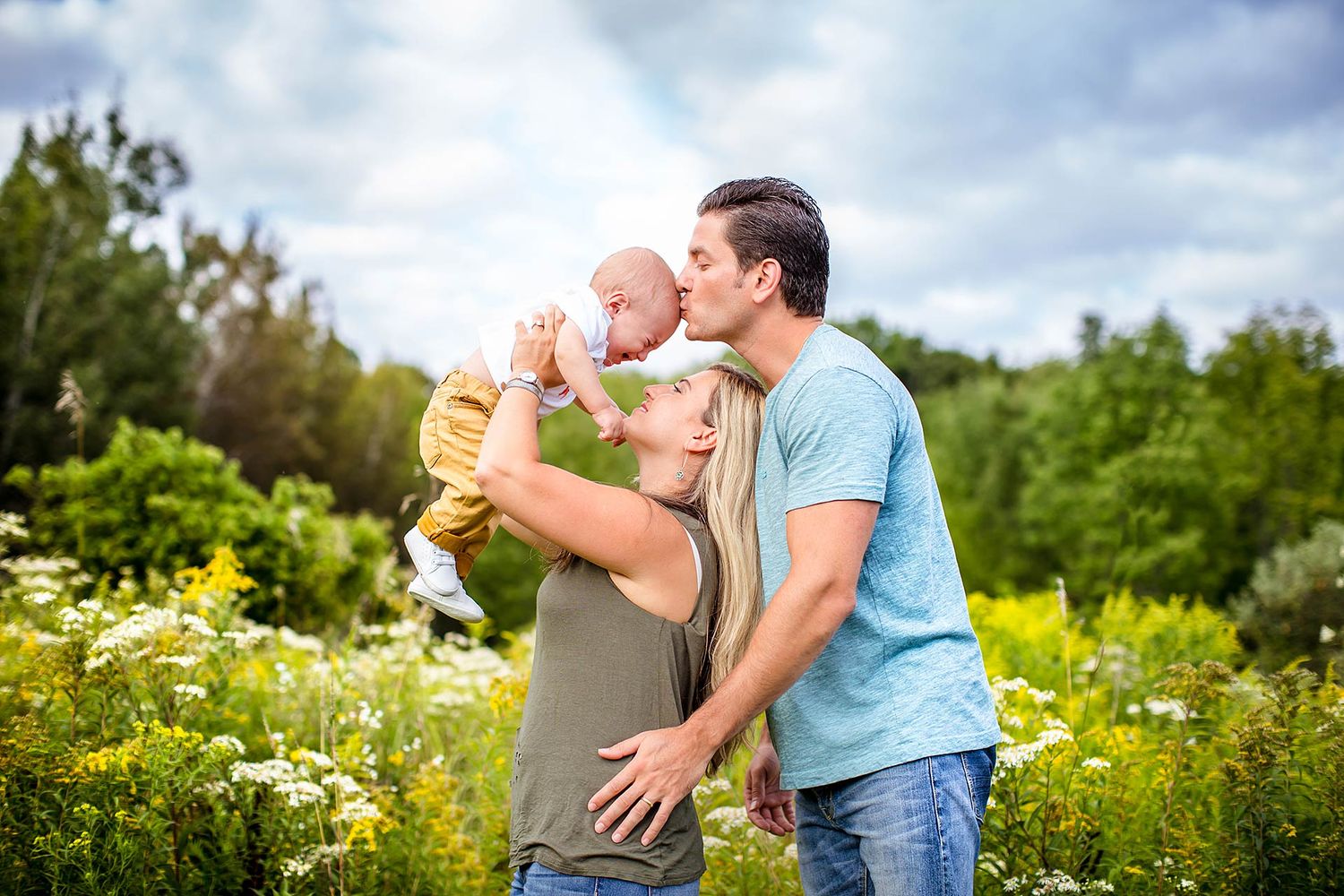 Family laying in grass during a sunny outdoor photo session.