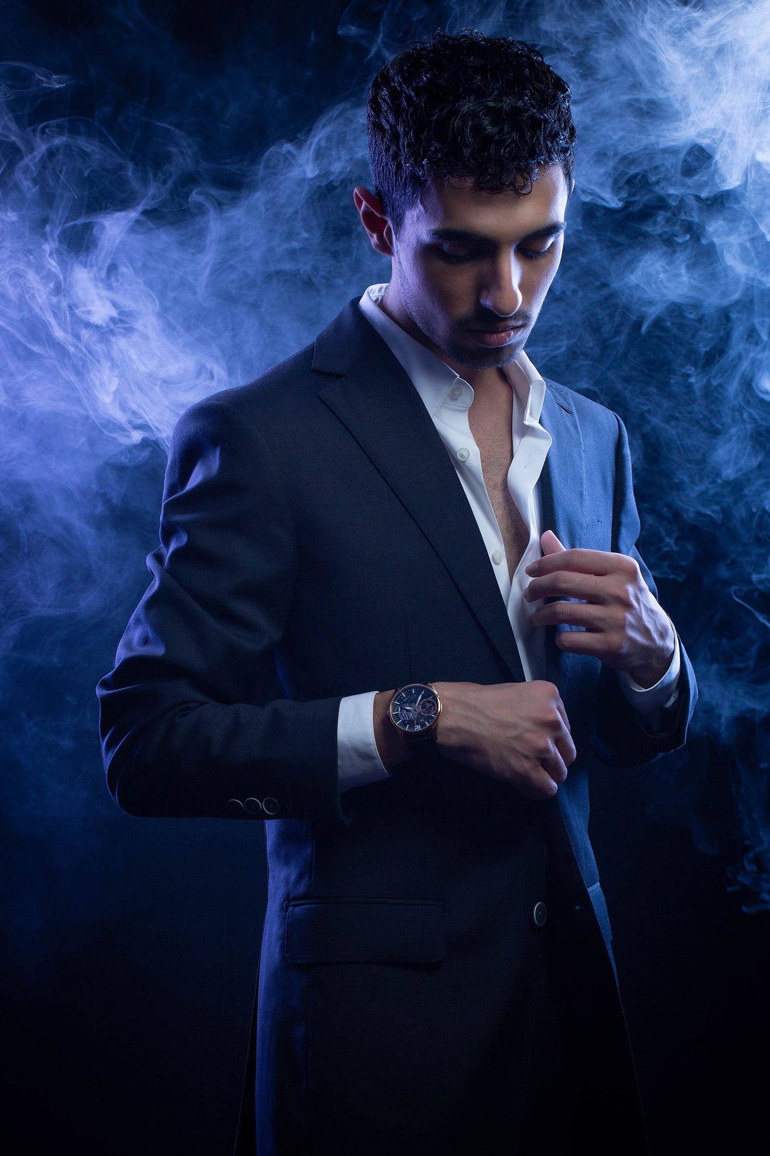 Moody business portrait series featuring dramatic blue smoke and suit silhouette.