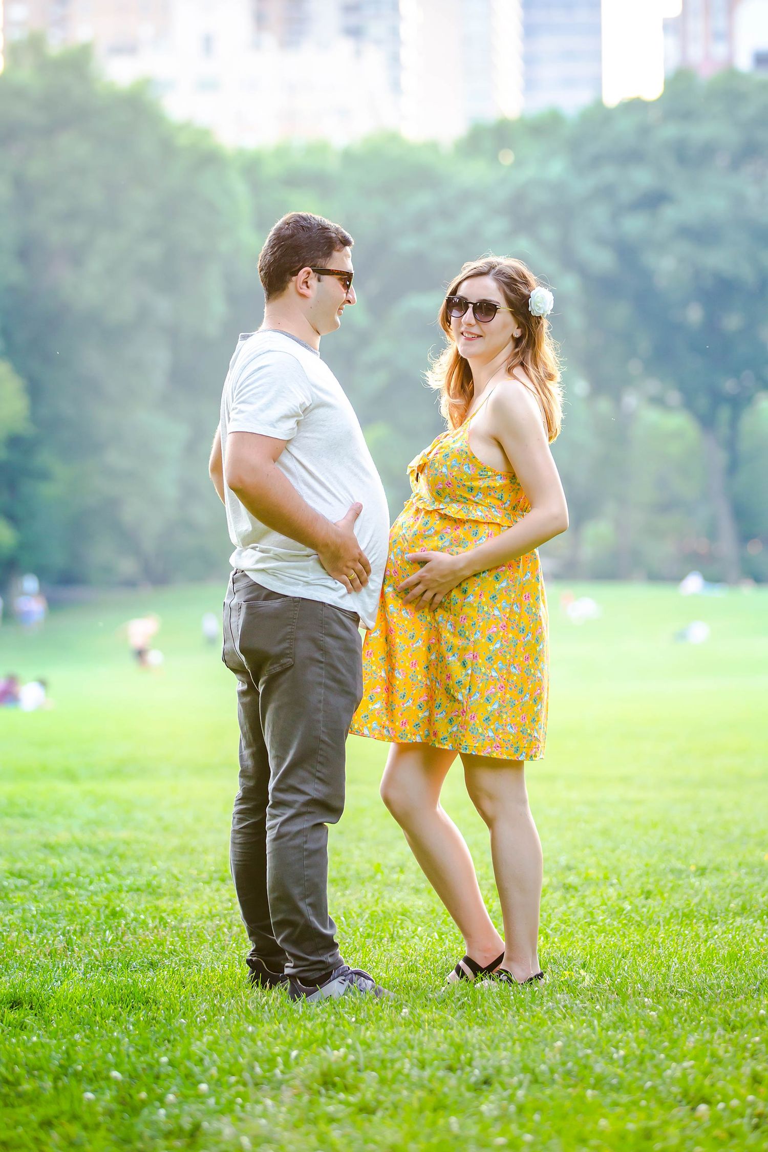 Candid moments of couple playing in park with urban backdrop.