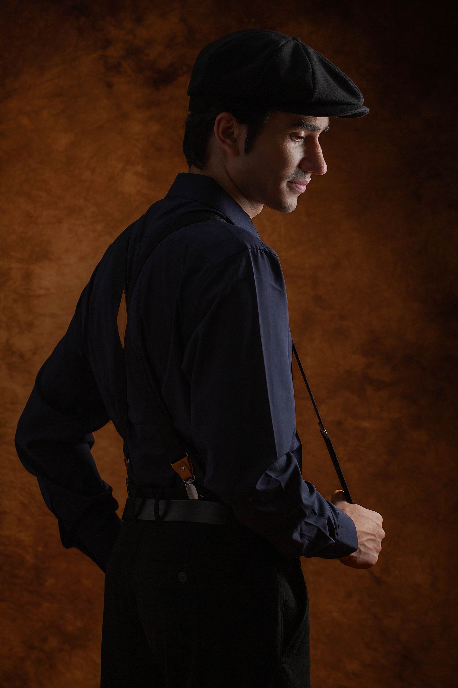 Silhouetted figure in dark clothing and cap shown in dramatic studio lighting sequence.