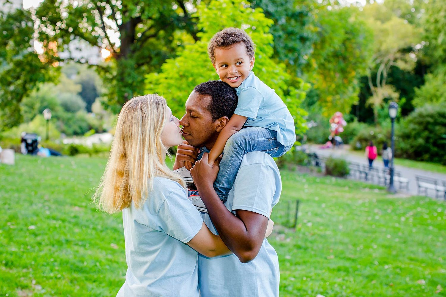 Family sharing playful moments together in outdoor park setting.