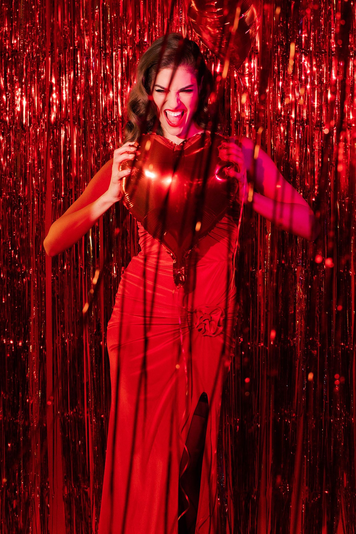 Dancing figure in red dress against sparkly red tinsel backdrop.