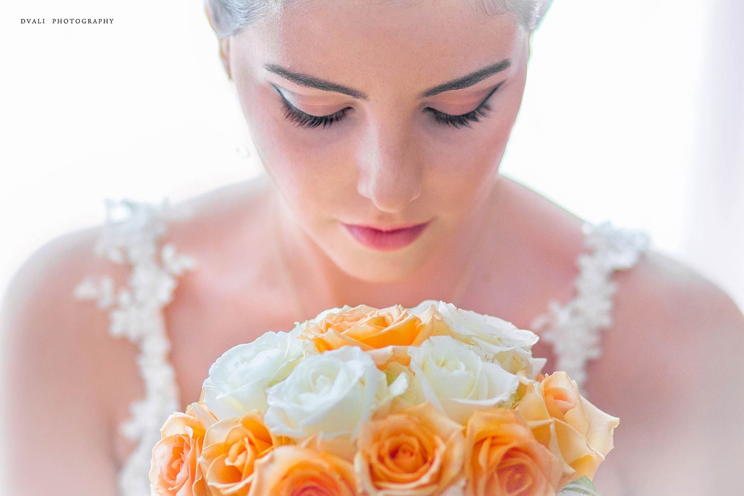 Close-up view of a bridal bouquet featuring peach roses and white flowers against a bright background.