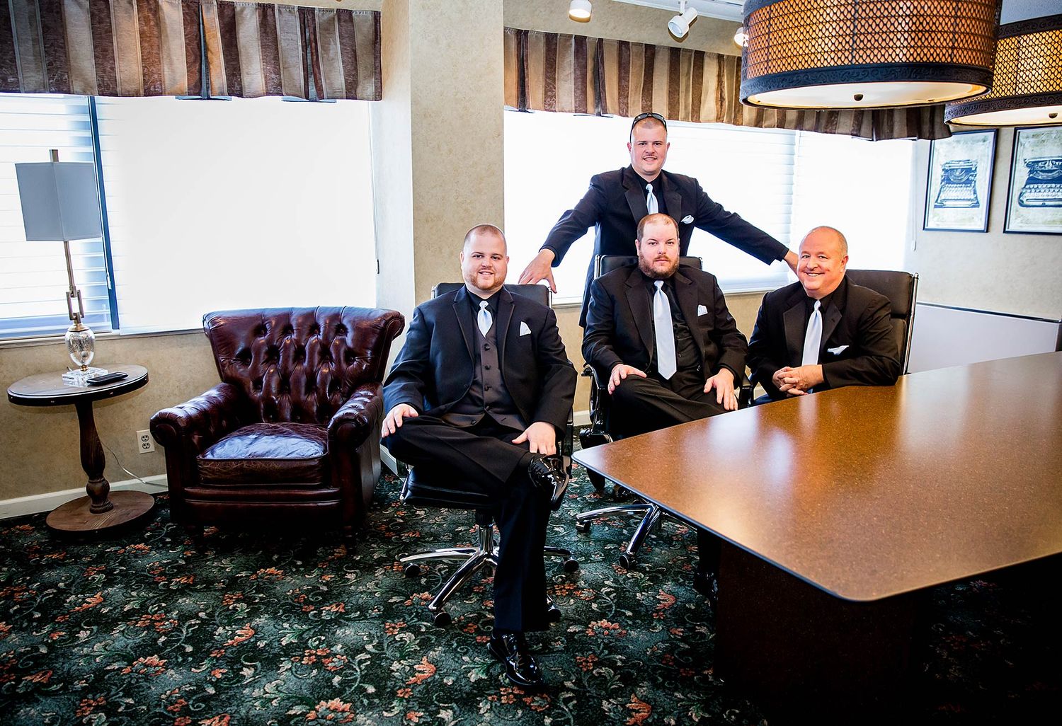 Wedding party in formal attire relaxing on leather furniture in an elegant room.