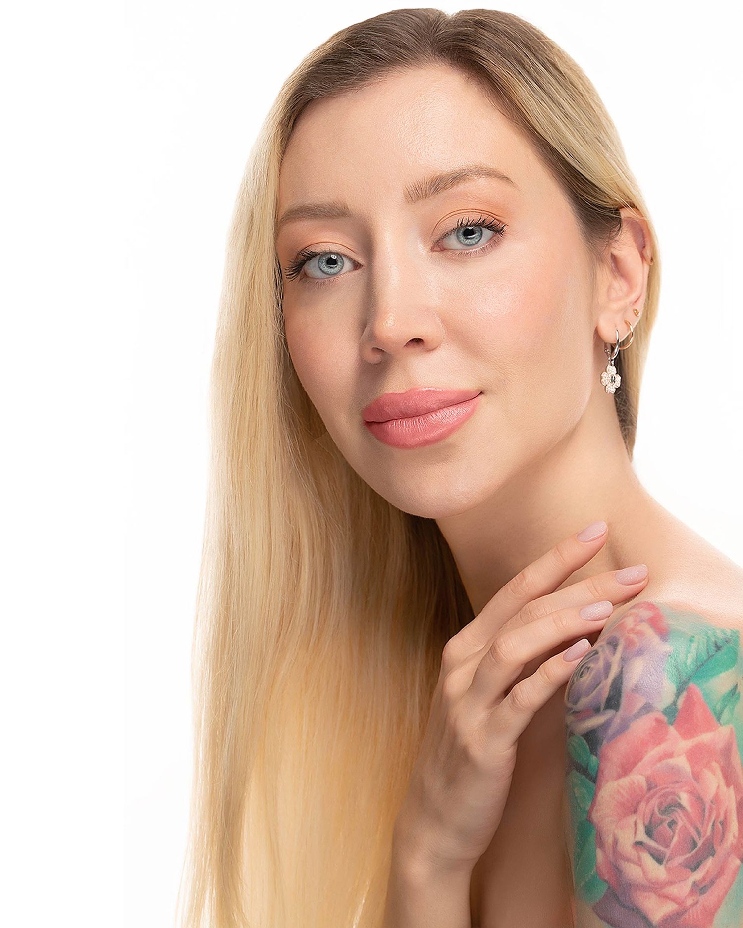 Elegant beauty portrait with long blonde hair, natural makeup and visible floral tattoo.
