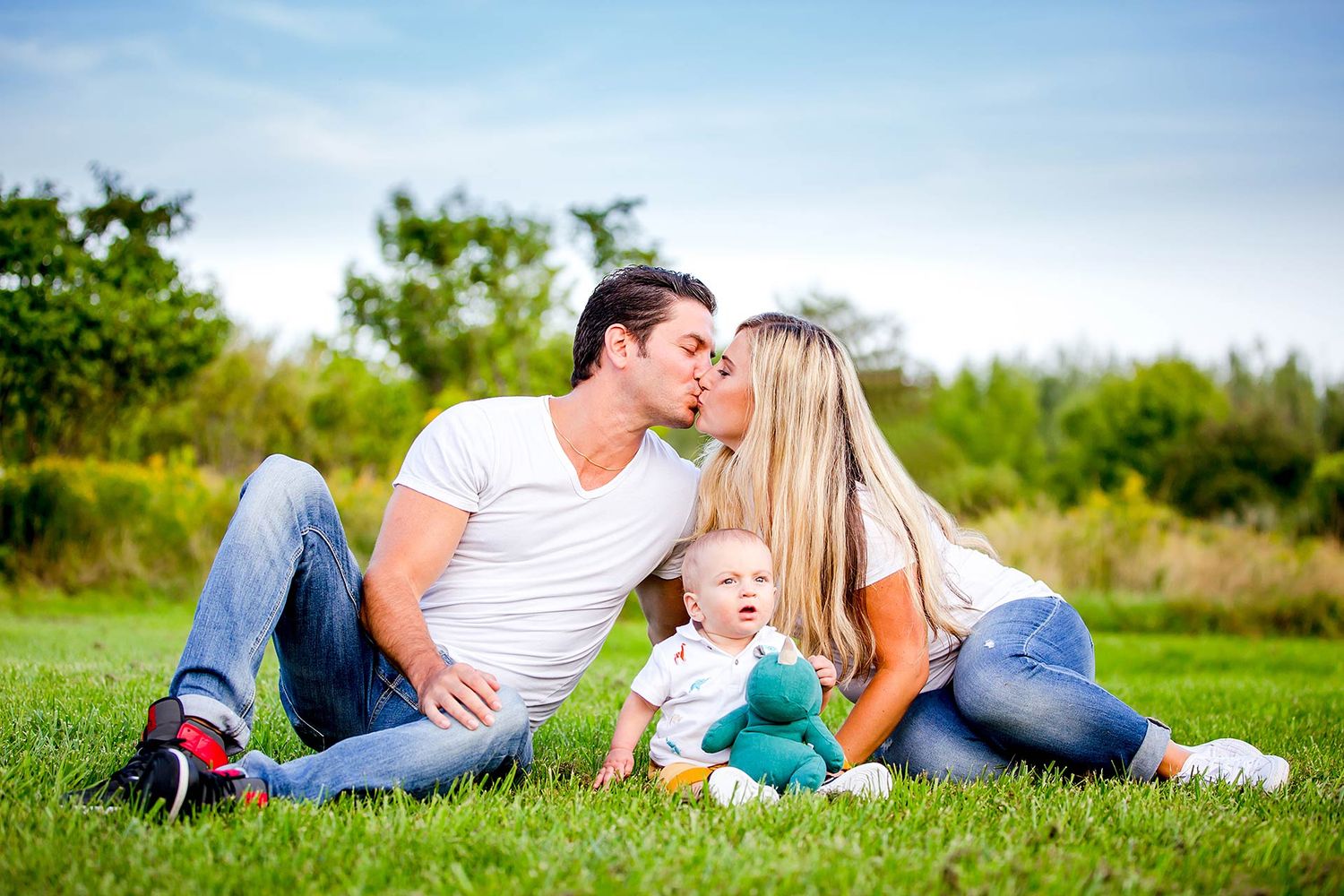 Family relaxing together on grass during an outdoor photo shoot.