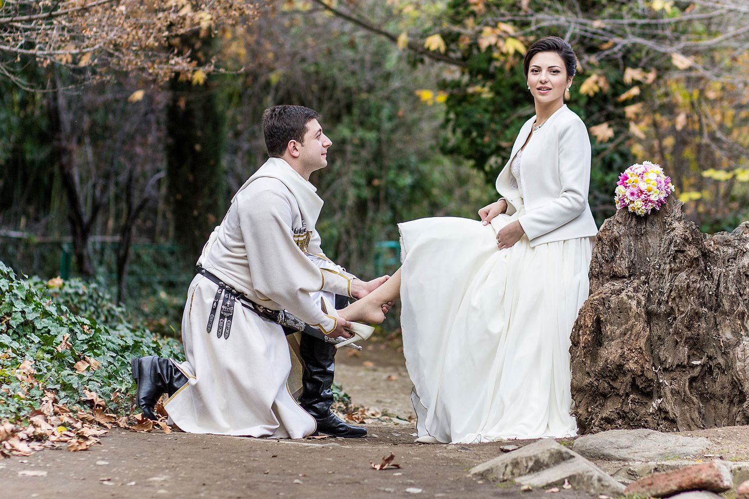 A romantic medieval proposal scene on a dirt path surrounded by autumn foliage.