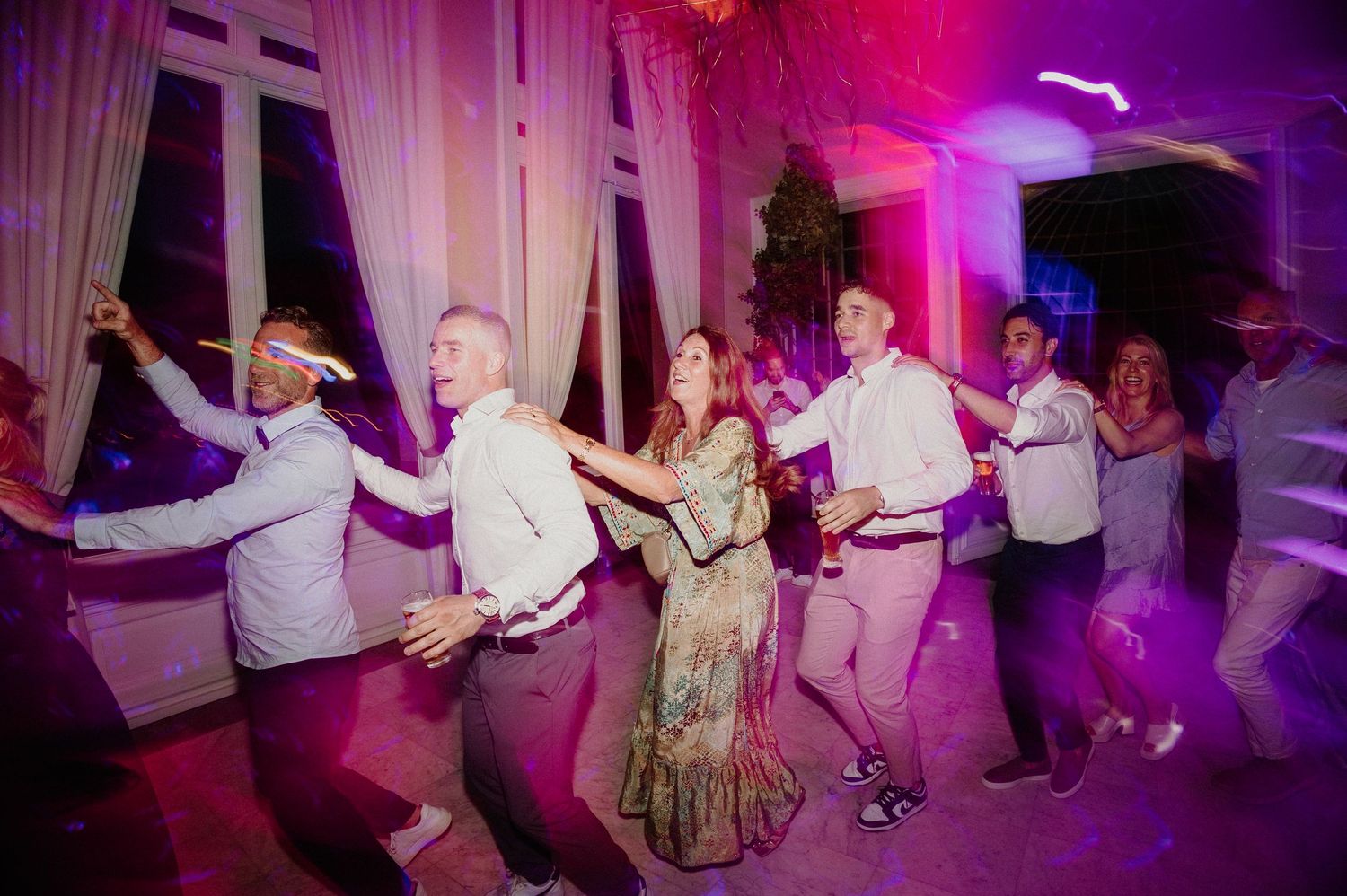 Gasten dansen de polonaise op de dansvloer tijdens het trouwfeest.