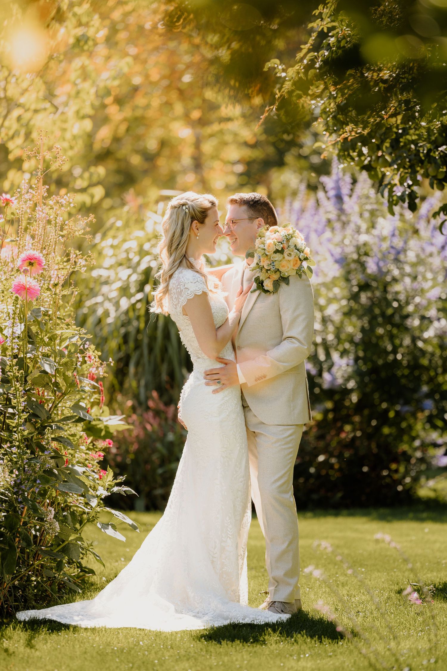 Een bruidspaar staat in een weelderige tuin vol bloemen